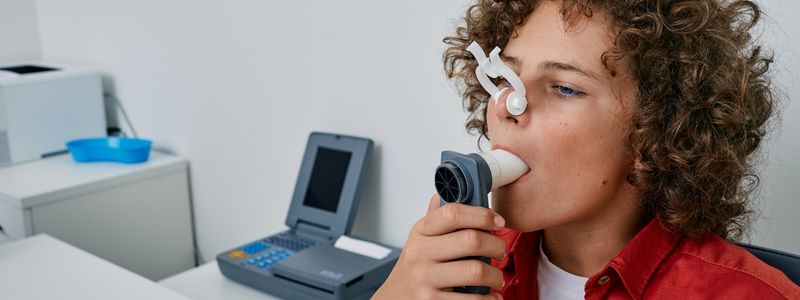 Ein Junge macht in der Kinderpneumologie einen Test zur Lungenstärke.