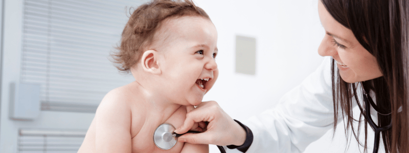 Baby wird untersucht und lächelt dabei.